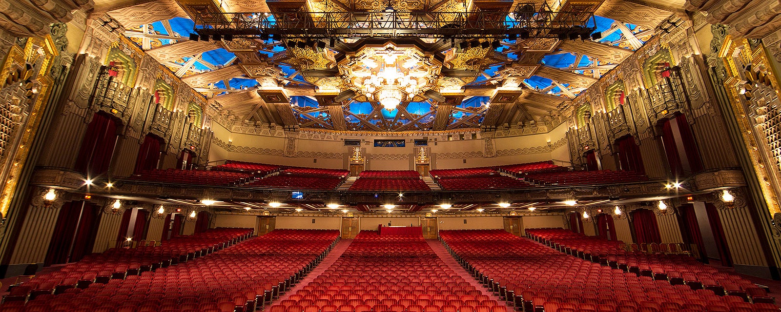 Hollywood Pantages Theatre auditorium with red seats beneath a gilded Art Deco ceiling, blue insets, and a chandelier.