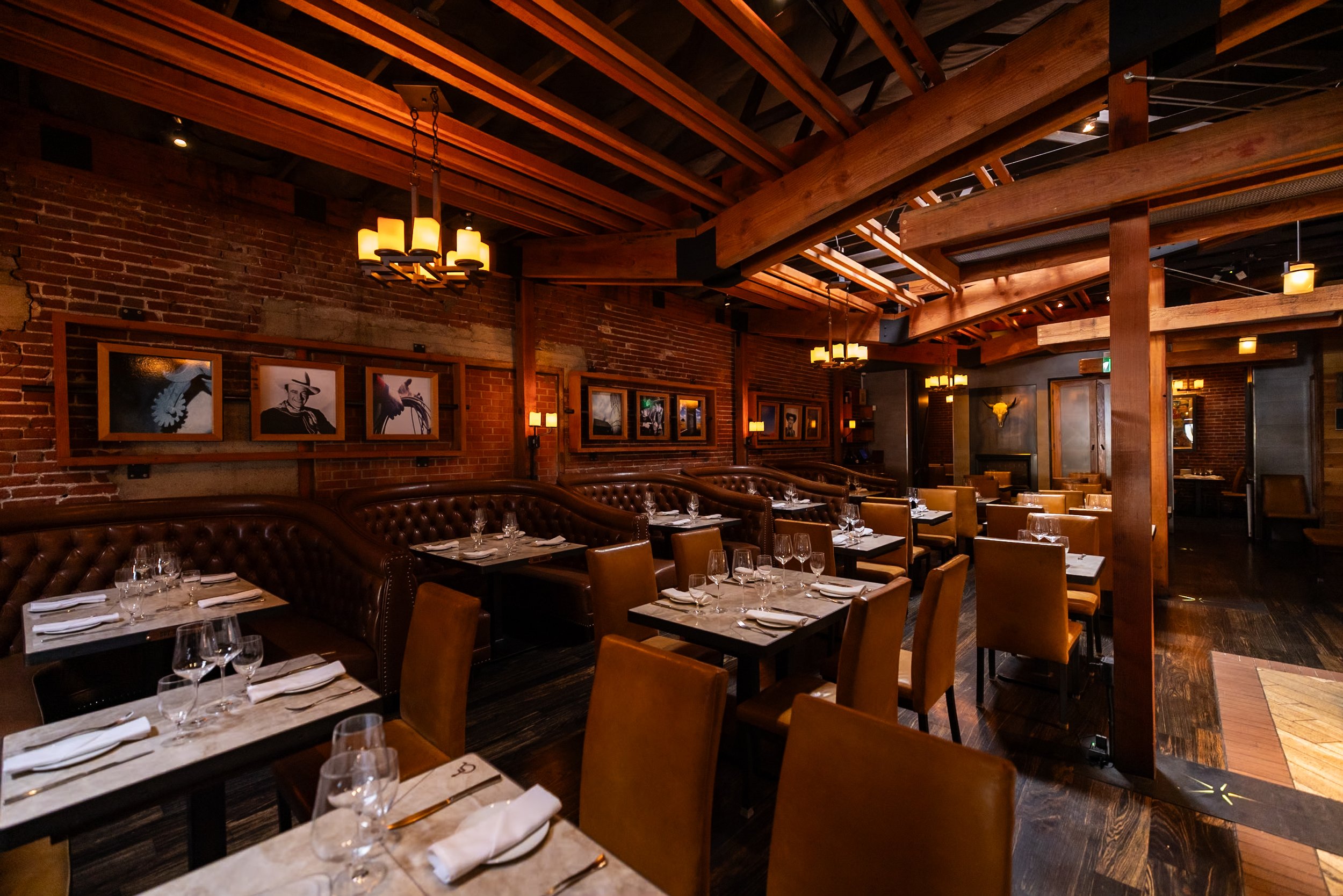 Cowboy Star dining room with exposed wooden beams, brick walls, leather booths and set tables