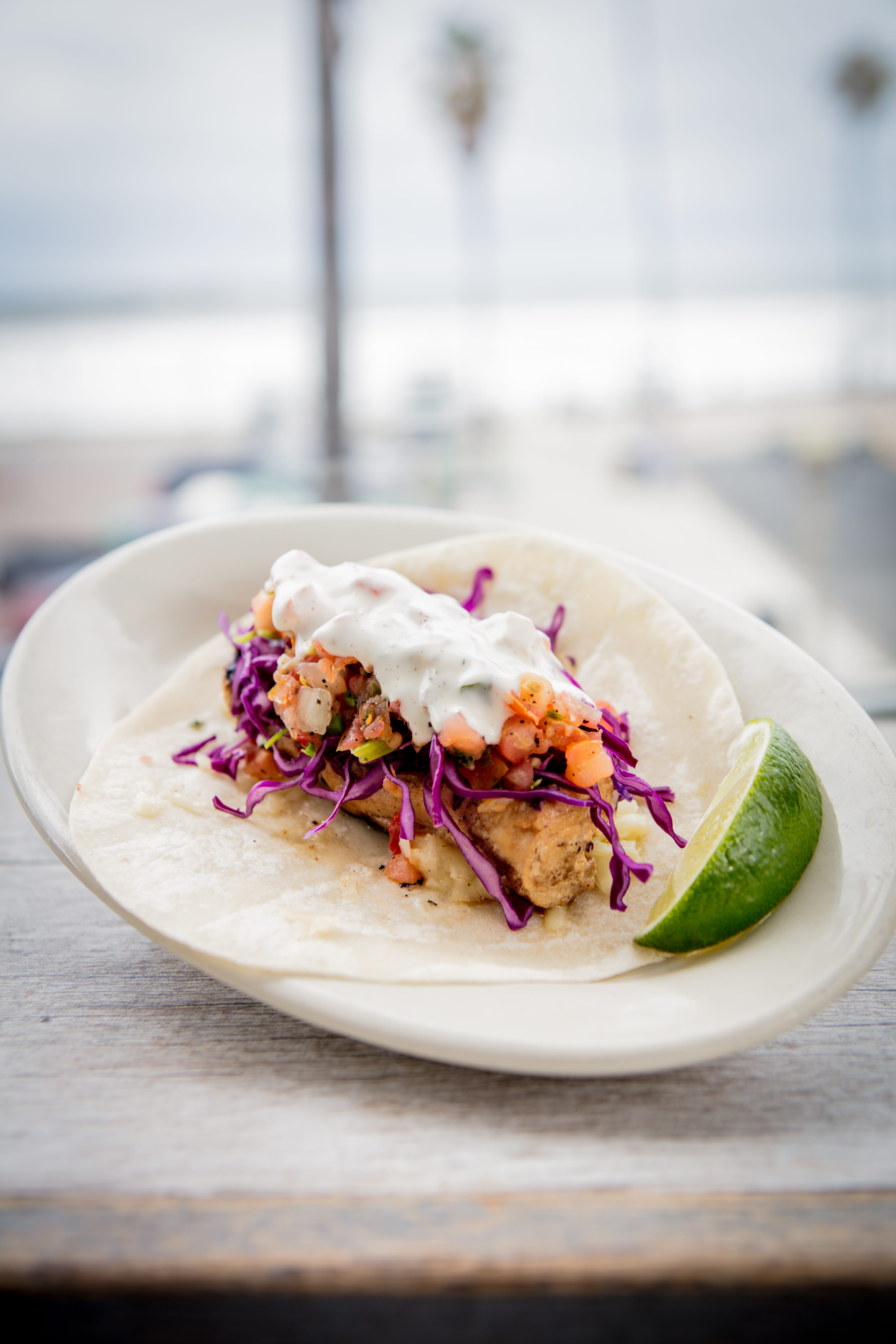 Fish taco topped with purple cabbage, pico de gallo and white sauce, served with lime at South Beach Bar & Grill